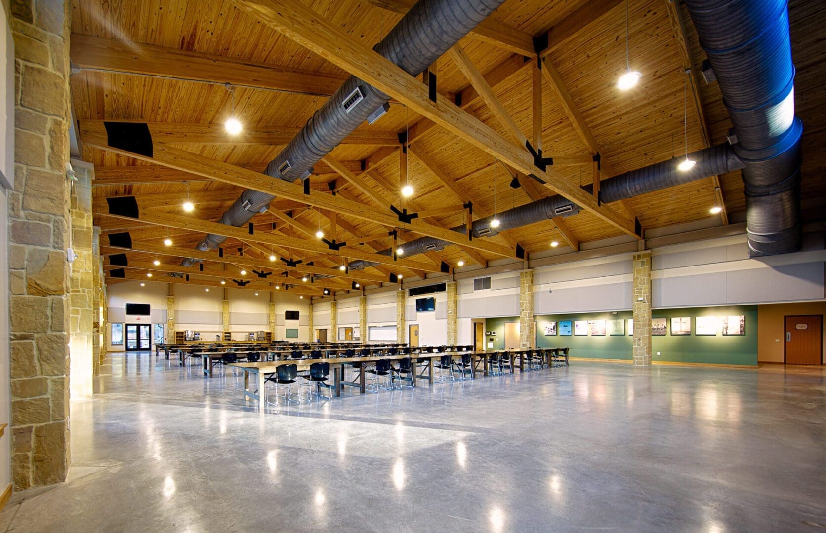 Spacious hall with wooden ceiling and tables.